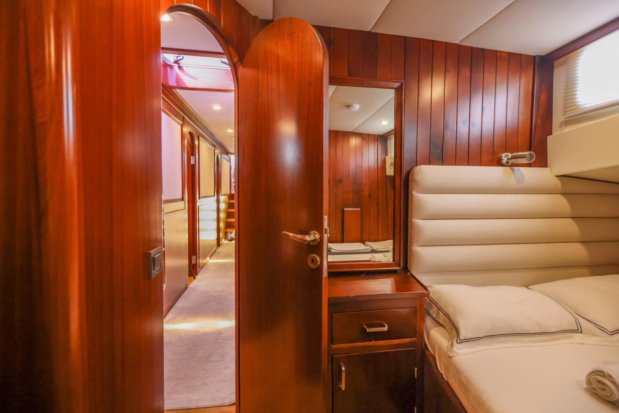 yacht guest cabin featuring single bed with cream upholstery and built-in storage drawers