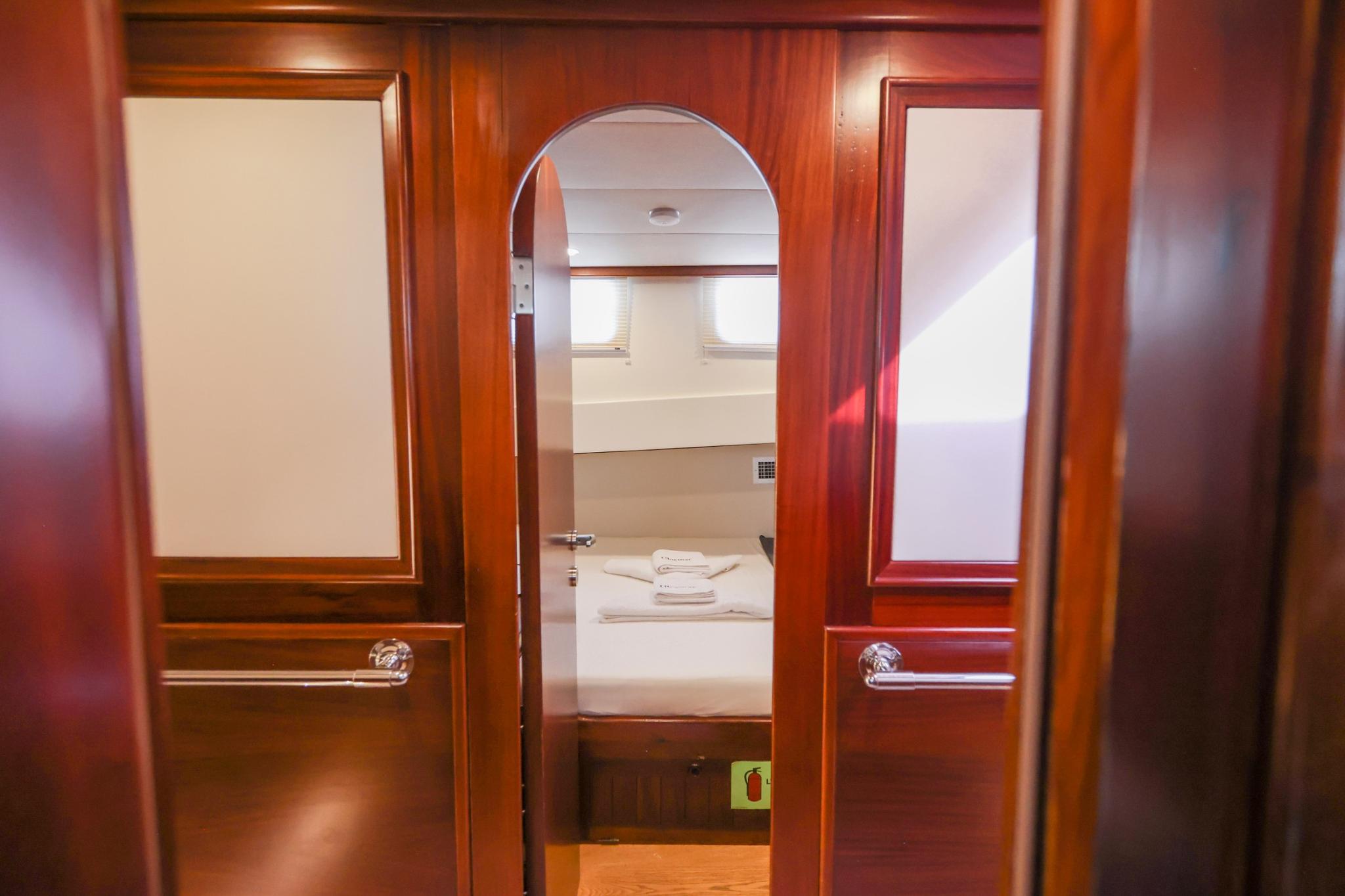 yacht cabin entrance featuring rich mahogany woodwork with arched doorway leading to bathroom with white towels