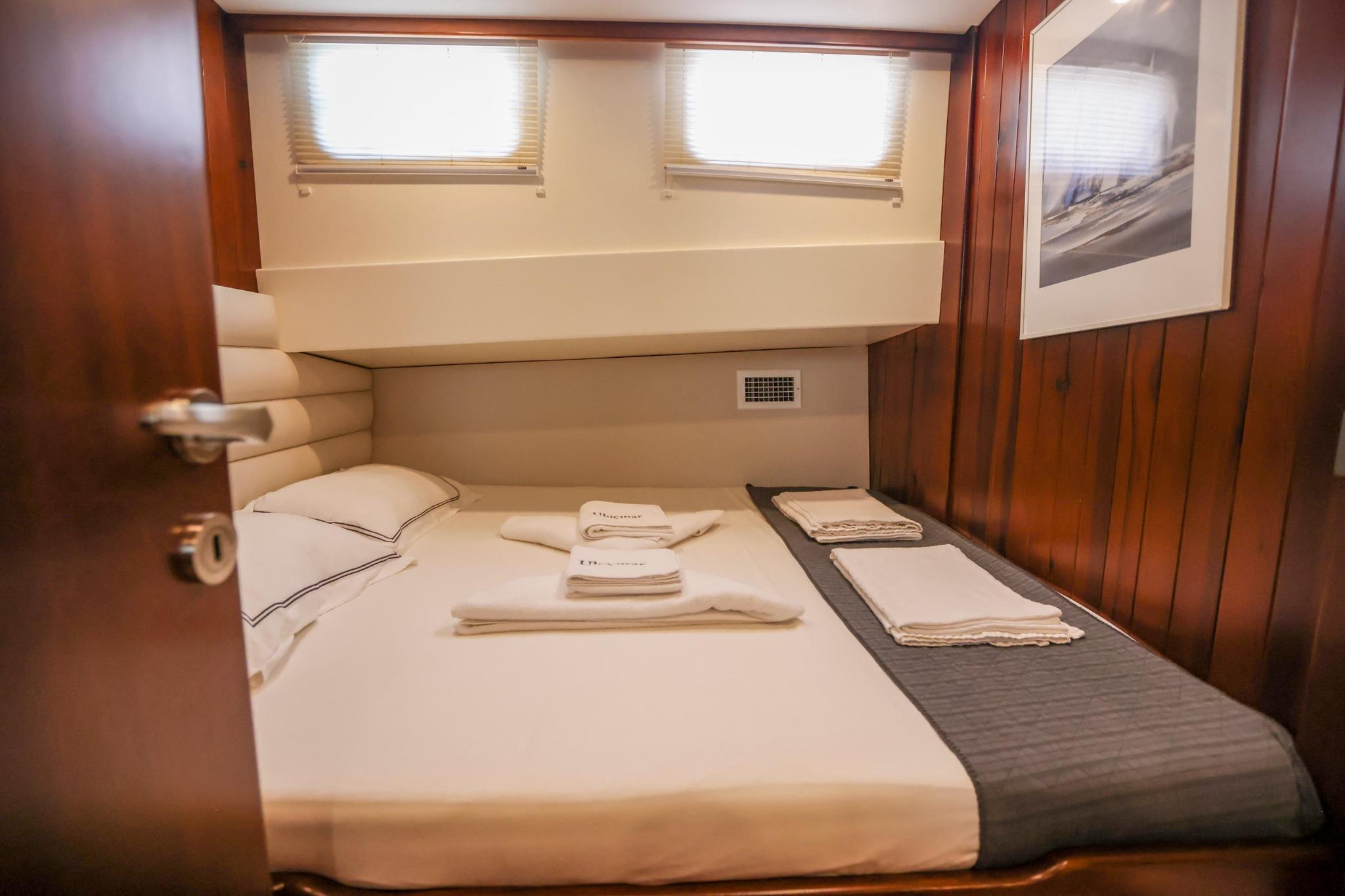 yacht guest cabin featuring double bed with white linens and cream leather headboard