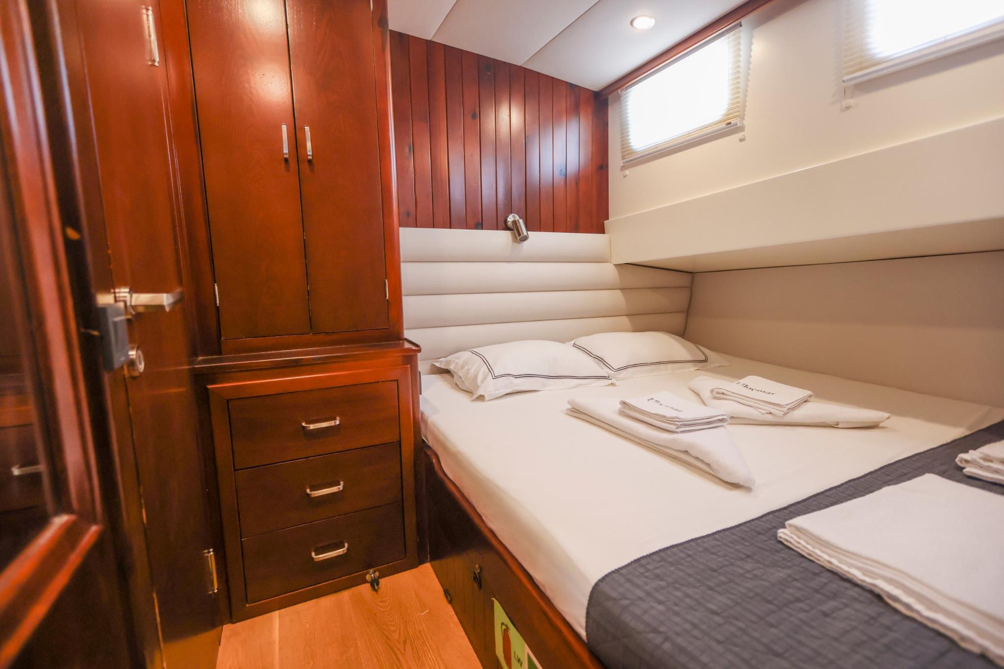 yacht guest cabin featuring double bed with white linens and built-in mahogany storage