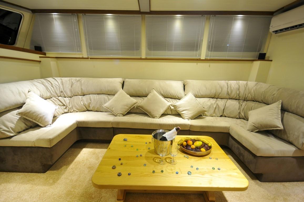 yacht salon interior with cream leather U-shaped sofa, yellow coffee table and horizontal blinds