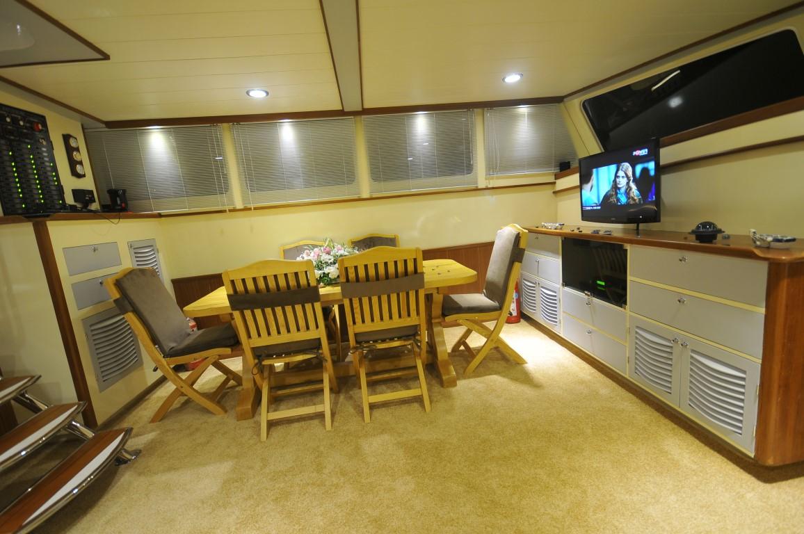 yacht cinema room with large wall-mounted television and wooden dining table seating