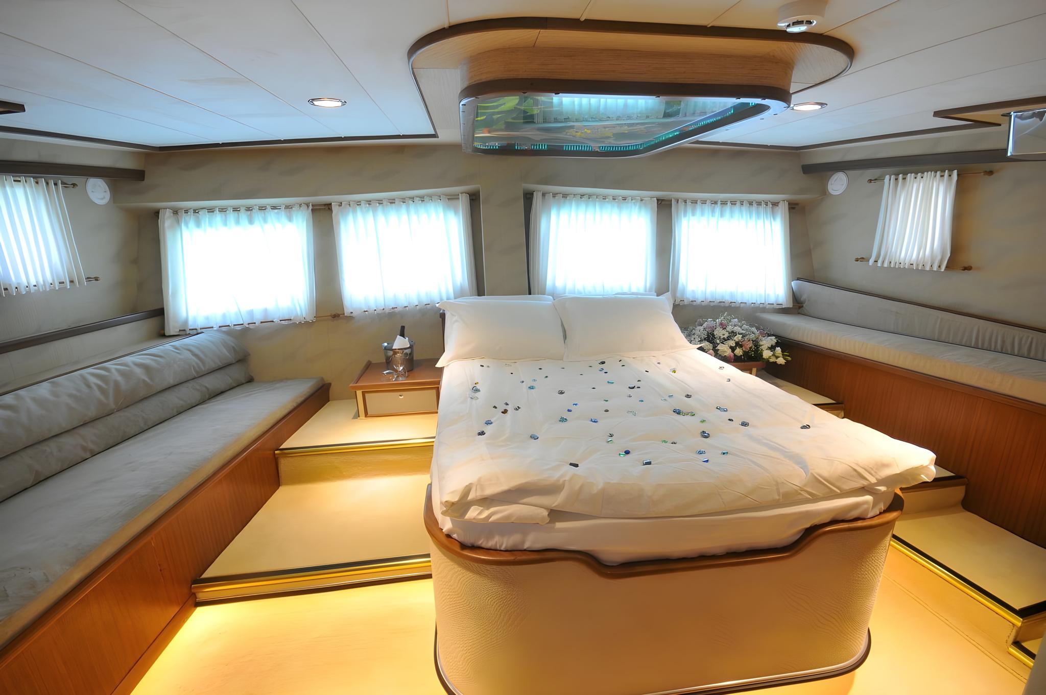 luxury yacht master cabin featuring double bed with white linens, built-in seating, panoramic windows