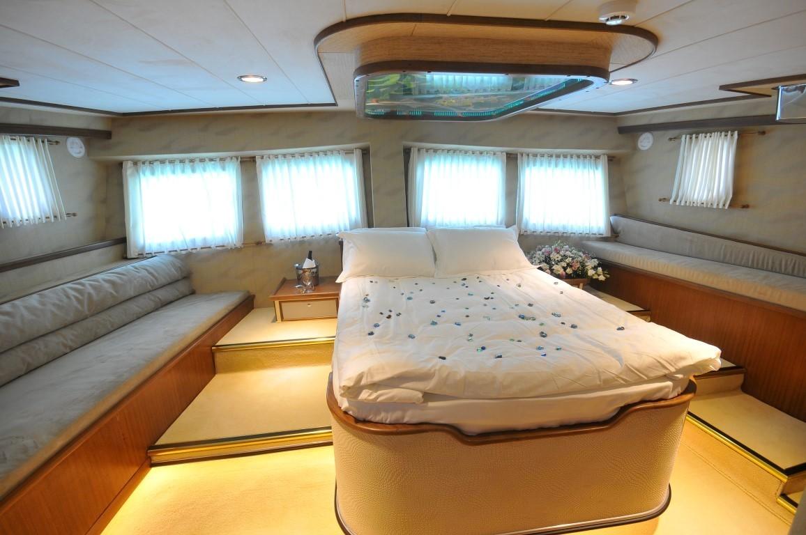 luxury yacht master cabin featuring double bed with white linens, built-in seating, panoramic windows
