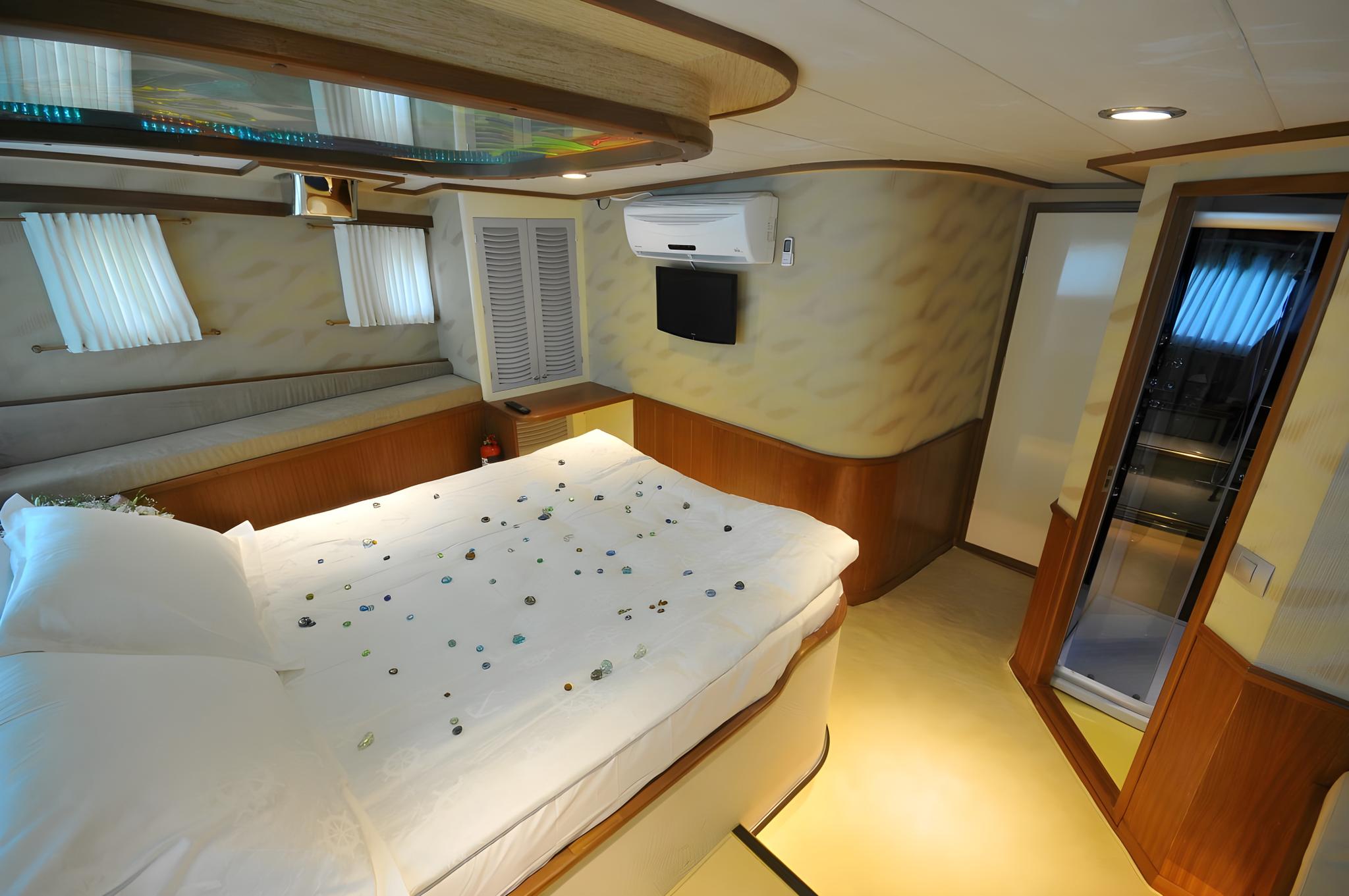 yacht cabin interior with double bed covered in scattered rose petals and white linens