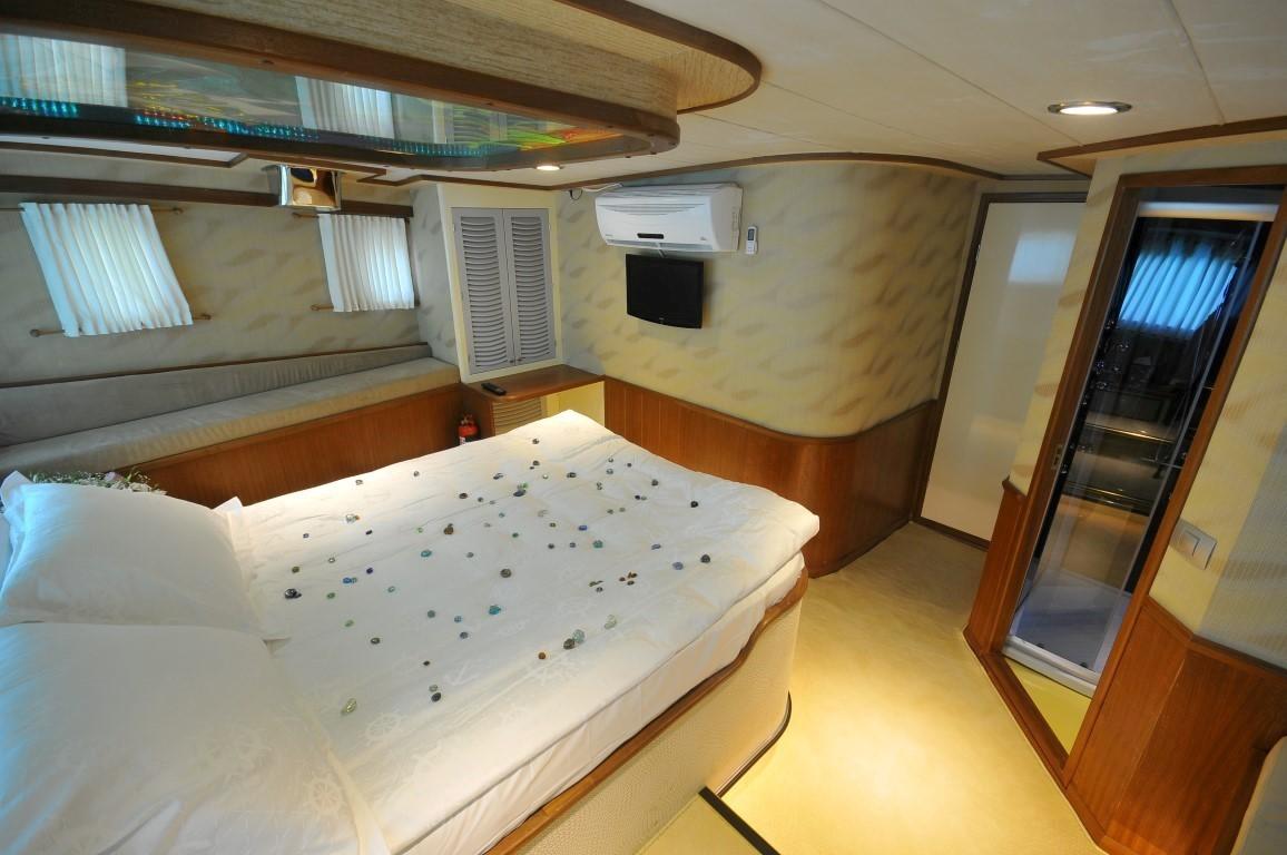 yacht cabin interior with double bed covered in scattered rose petals and white linens