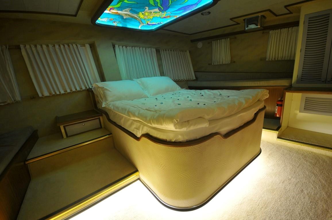yacht cabin interior featuring double bed with white linens and colorful LED ceiling display