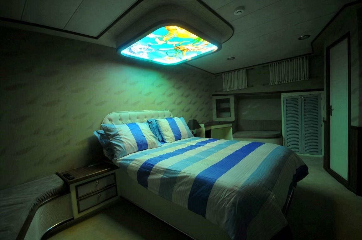 yacht guest cabin with double bed, striped bedding and illuminated ceiling skylight