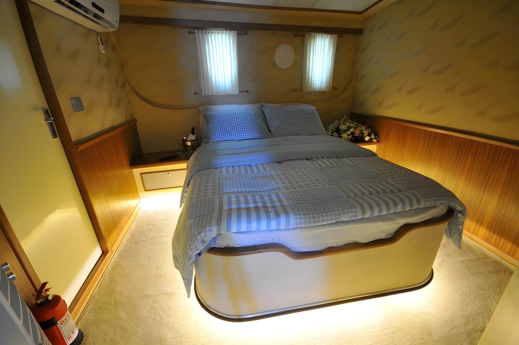yacht guest cabin featuring double bed with gray bedding and two round portholes
