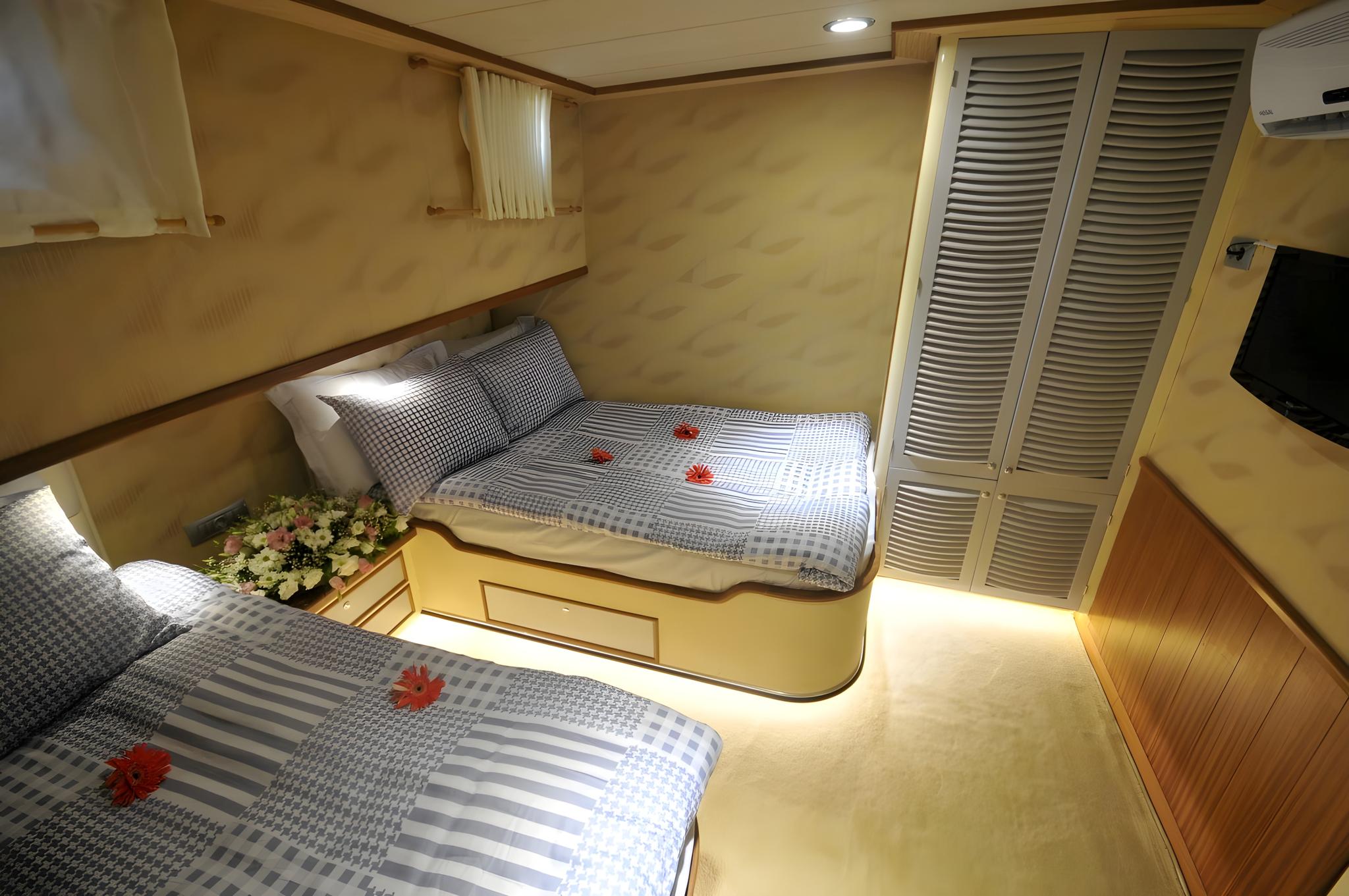 yacht guest cabin featuring twin beds with blue checkered bedding and white louvered wardrobes