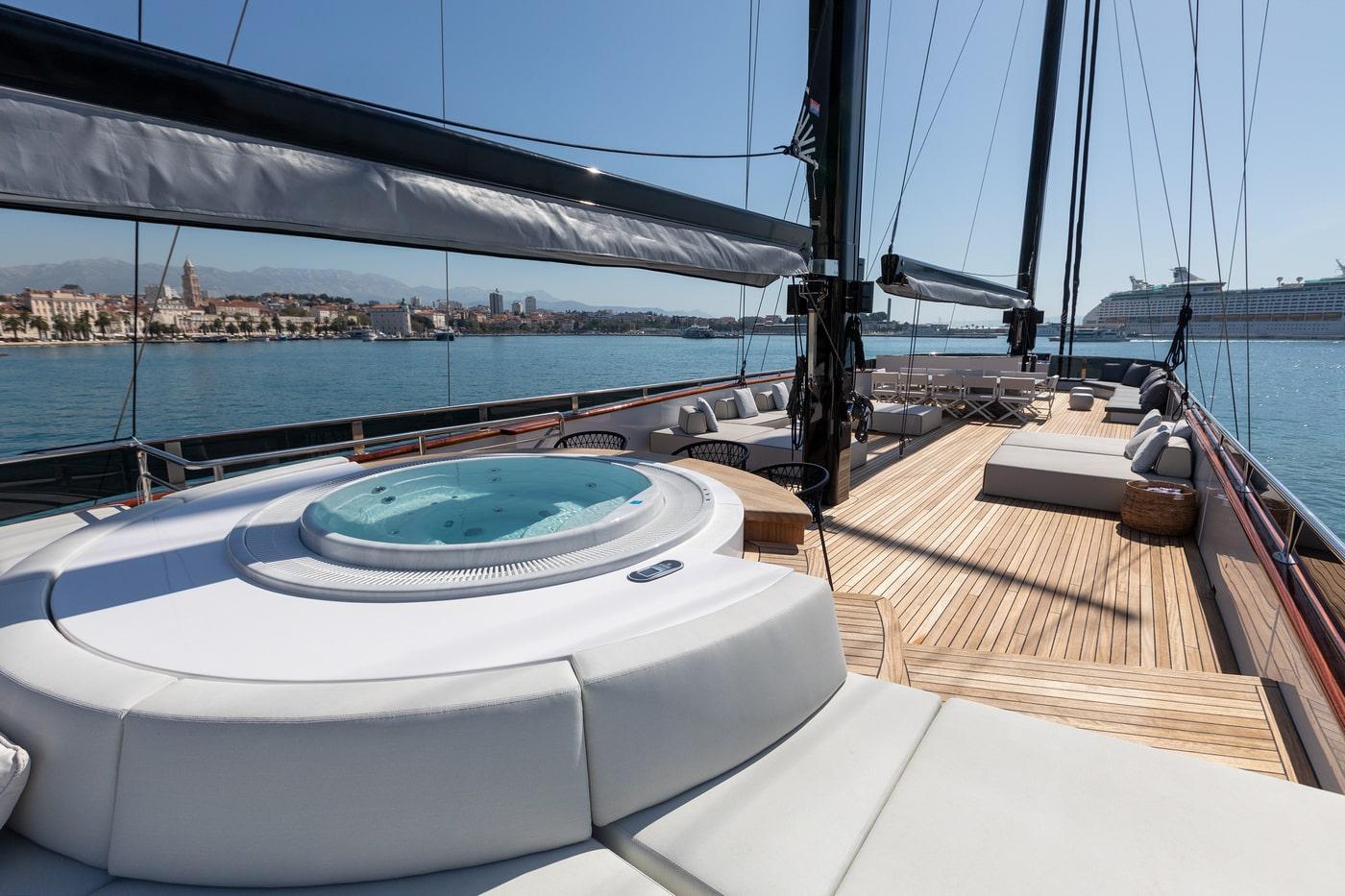 luxury sailing yacht deck featuring circular jacuzzi hot tub and teak flooring