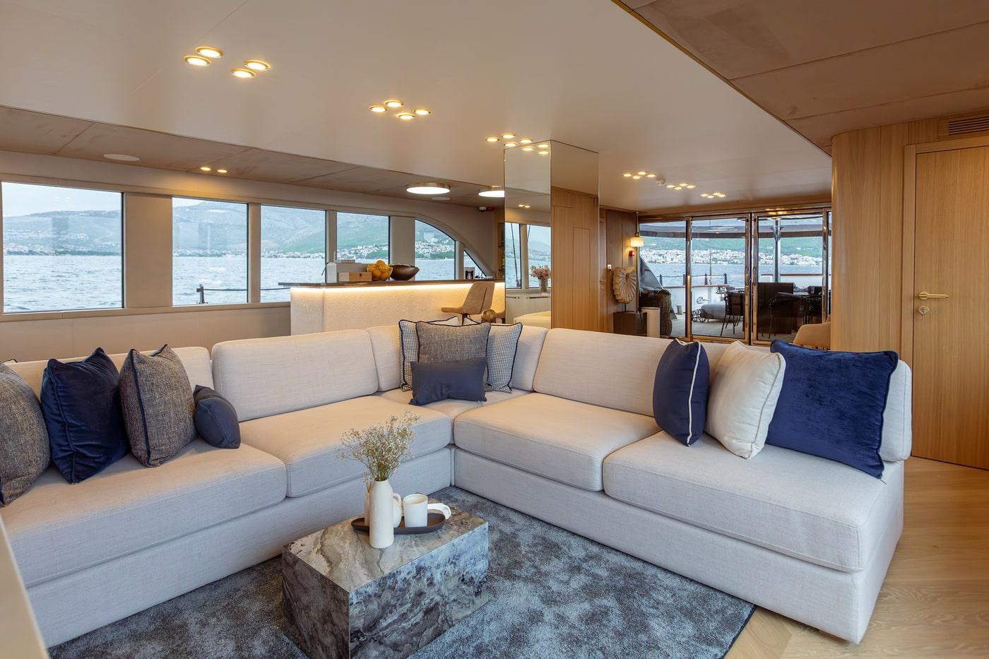 luxury yacht main salon with gray sectional sofa and panoramic windows