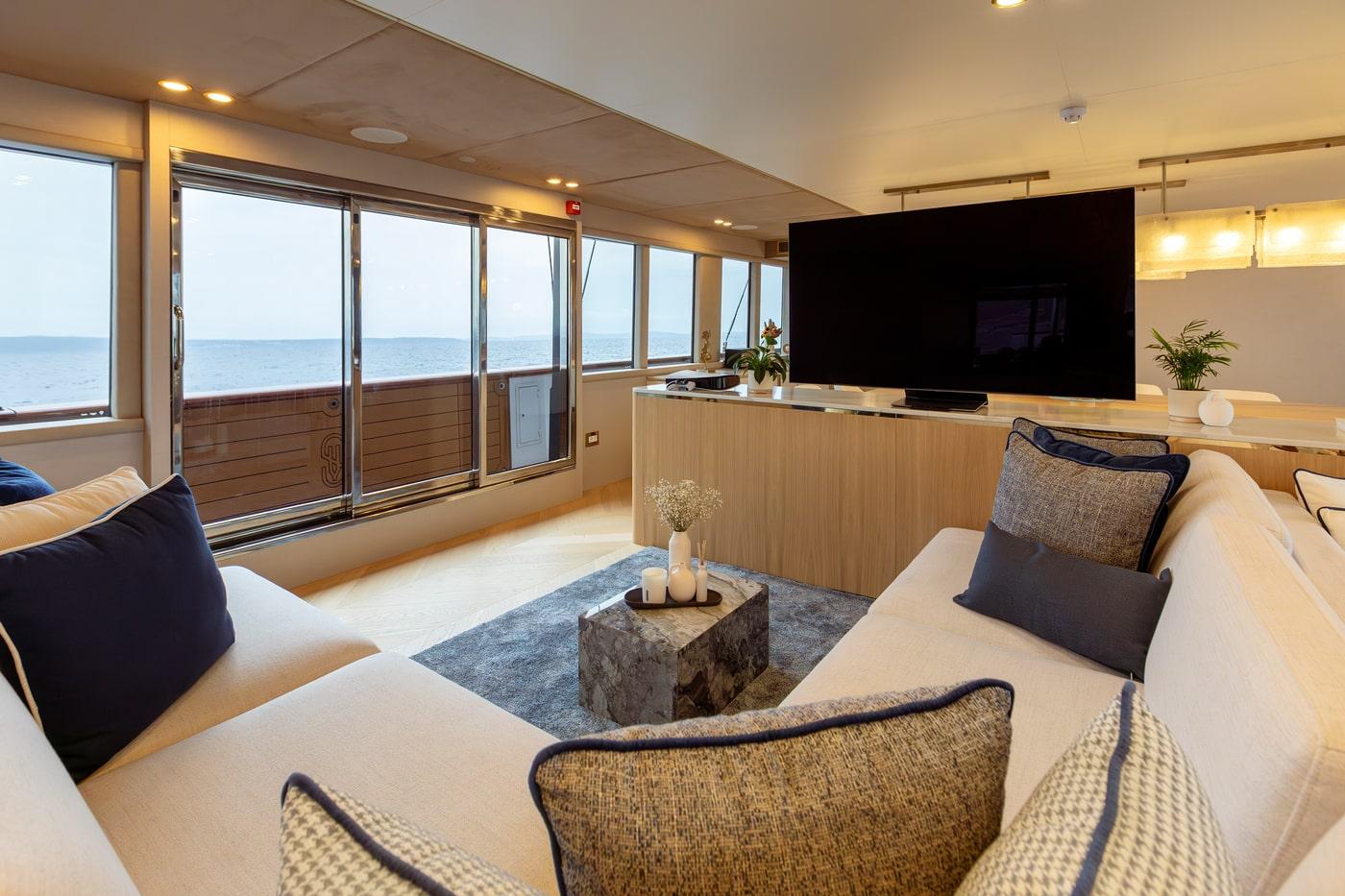 Modern yacht salon with cream sectional sofa, marble coffee table, panoramic ocean views