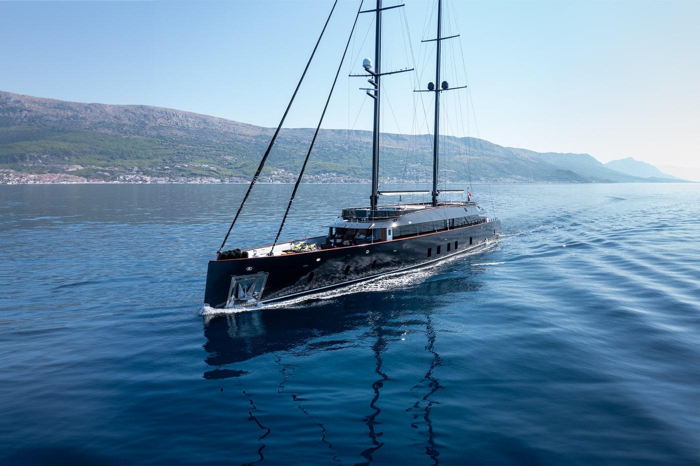 Large luxury sailing yacht with dark hull cruising on calm blue Mediterranean waters