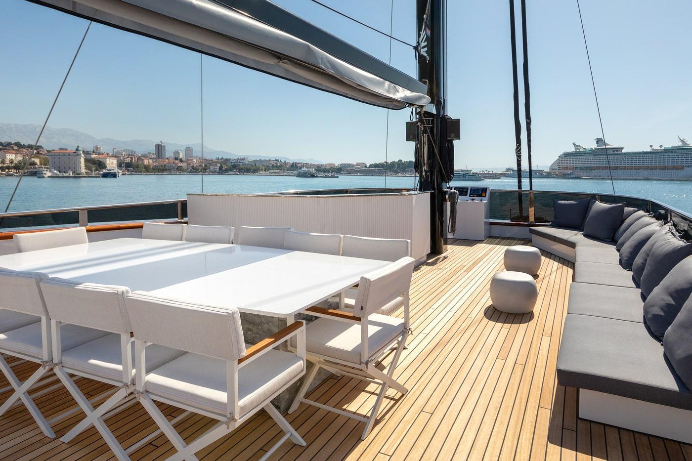 yacht aft deck with white dining table chairs and gray seating area