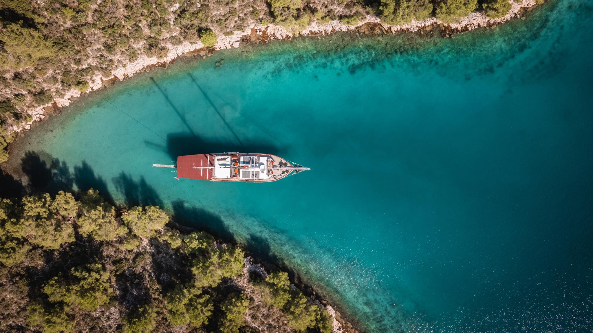 aerial view of traditional wooden gulet yacht anchored in crystal clear turquoise bay