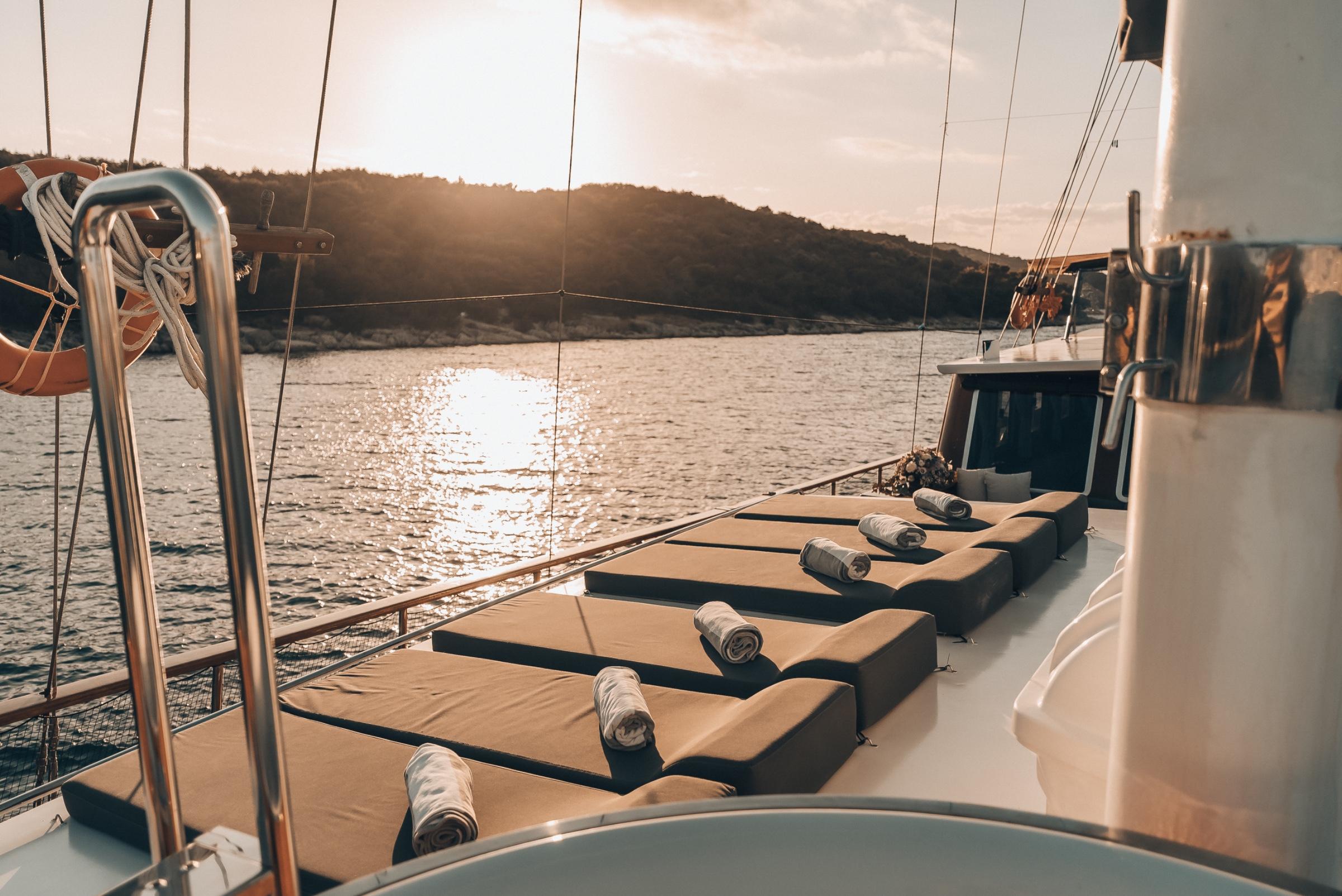 bow sun deck with beige cushioned loungers and rolled towels at golden hour