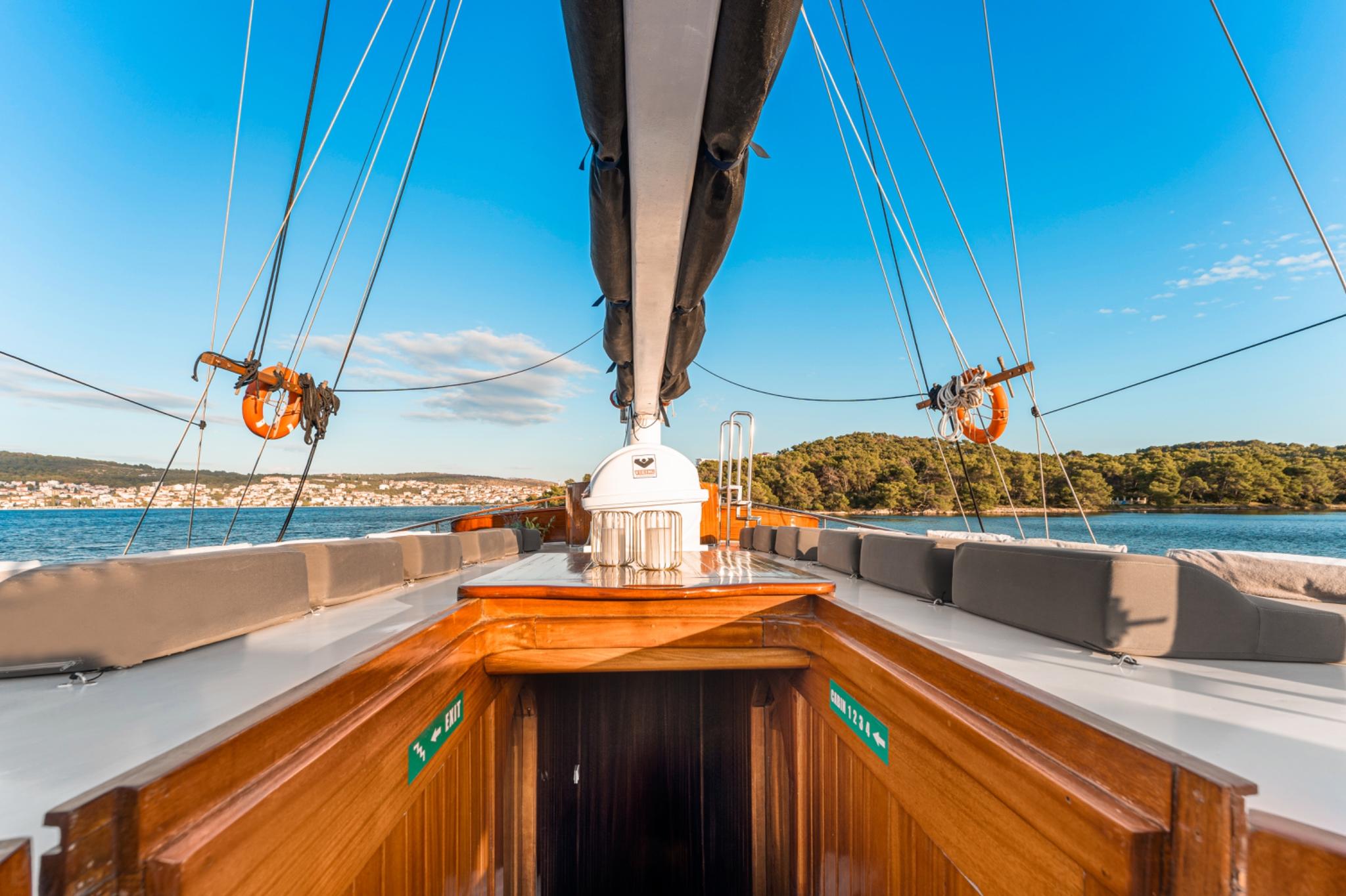 bow deck with curved seating, wooden companionway entrance and rigging visible