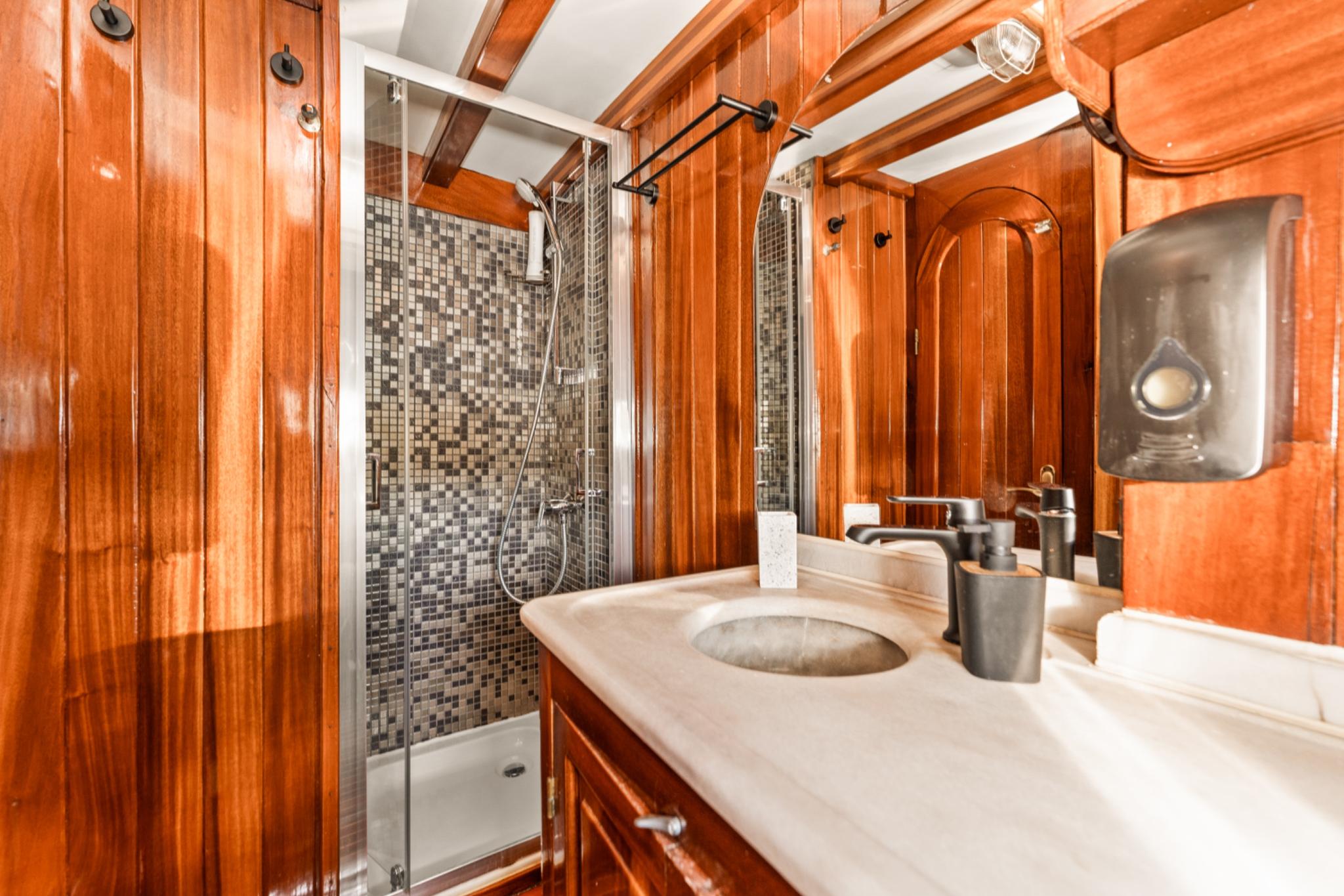 luxury yacht bathroom featuring marble vanity, mosaic tile shower, and rich wood paneling