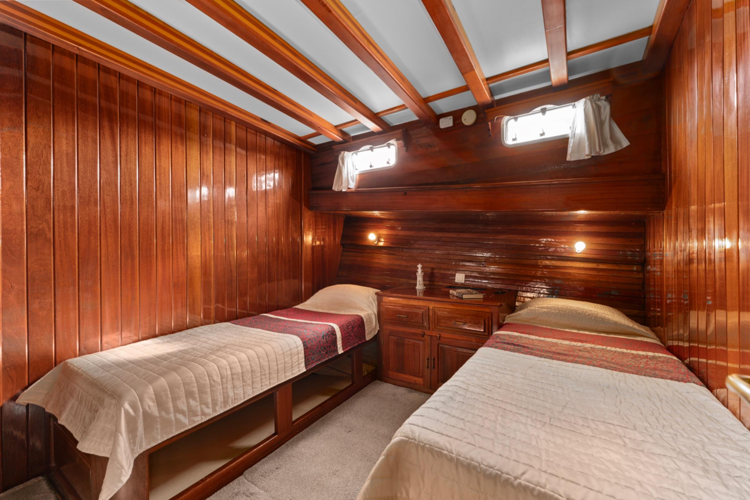 yacht twin cabin with two single beds, rich wooden paneling and exposed ceiling beams