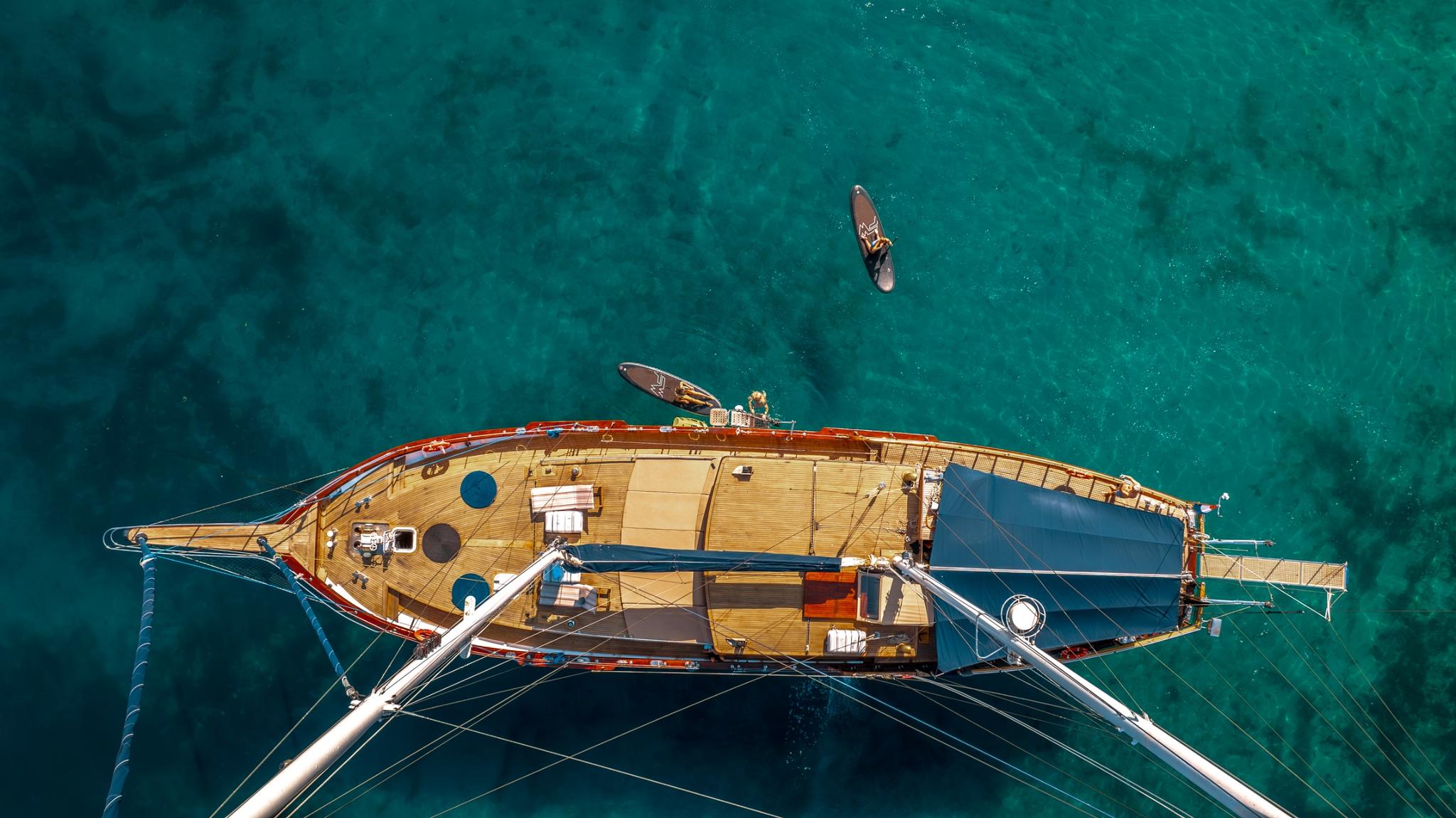 aerial drone shot of traditional wooden gulet yacht anchored in crystal clear turquoise Mediterranean waters