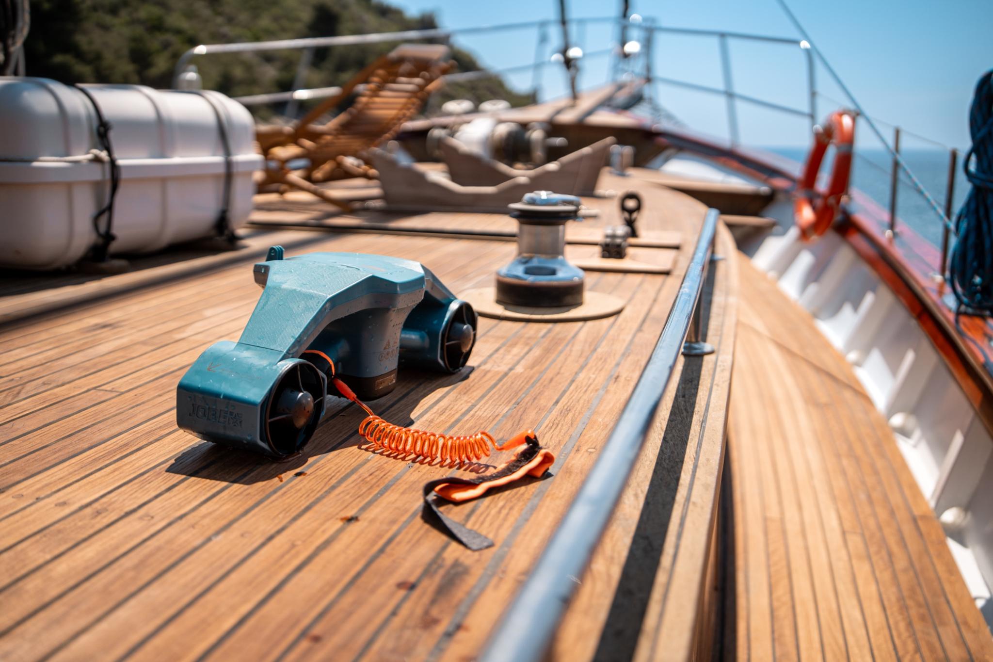 blue underwater sea scooter water toy on teak deck with orange coiled safety lanyard