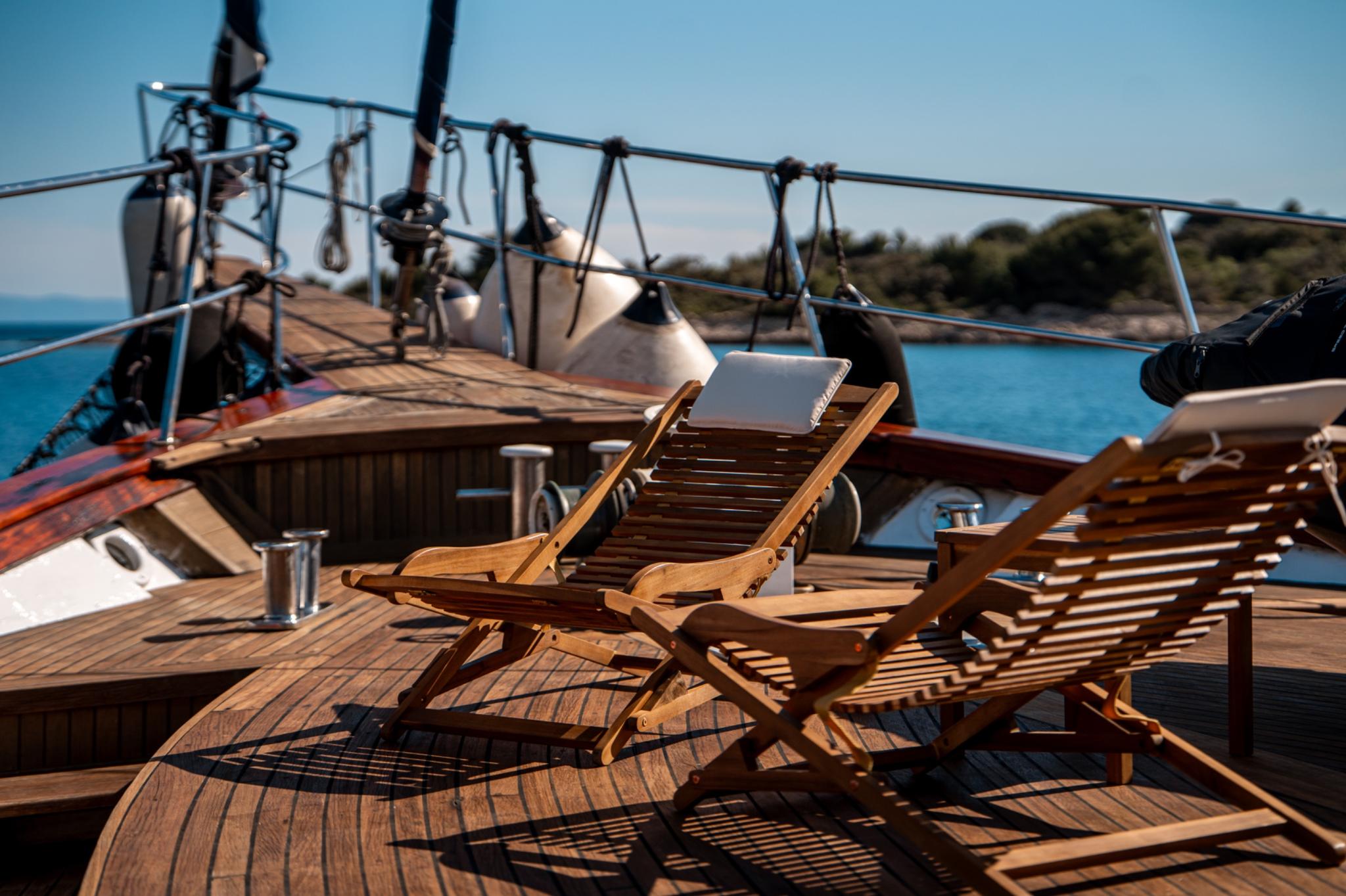 gulet sun deck with teak loungers, stainless steel rigging, and coastal backdrop