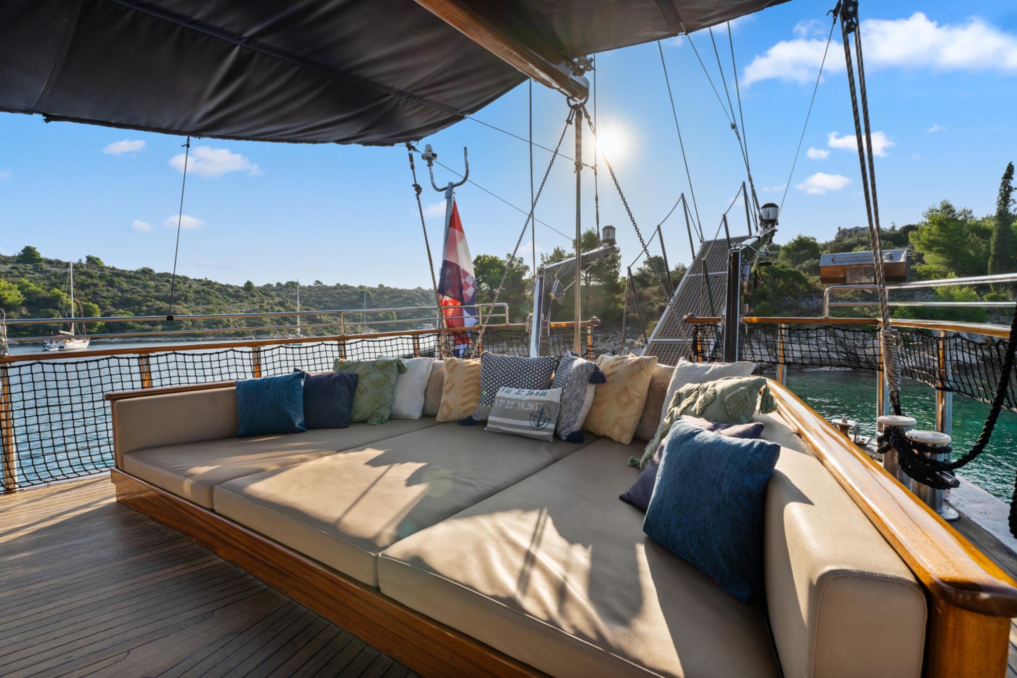 yacht aft deck outdoor lounge seating with beige cushions and colorful pillows under canvas awning