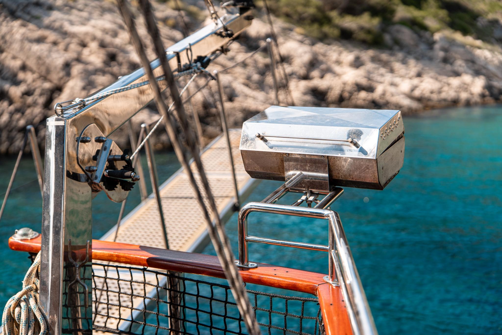 yacht stern deck featuring stainless steel barbecue grill and orange safety netting overlooking turquoise waters