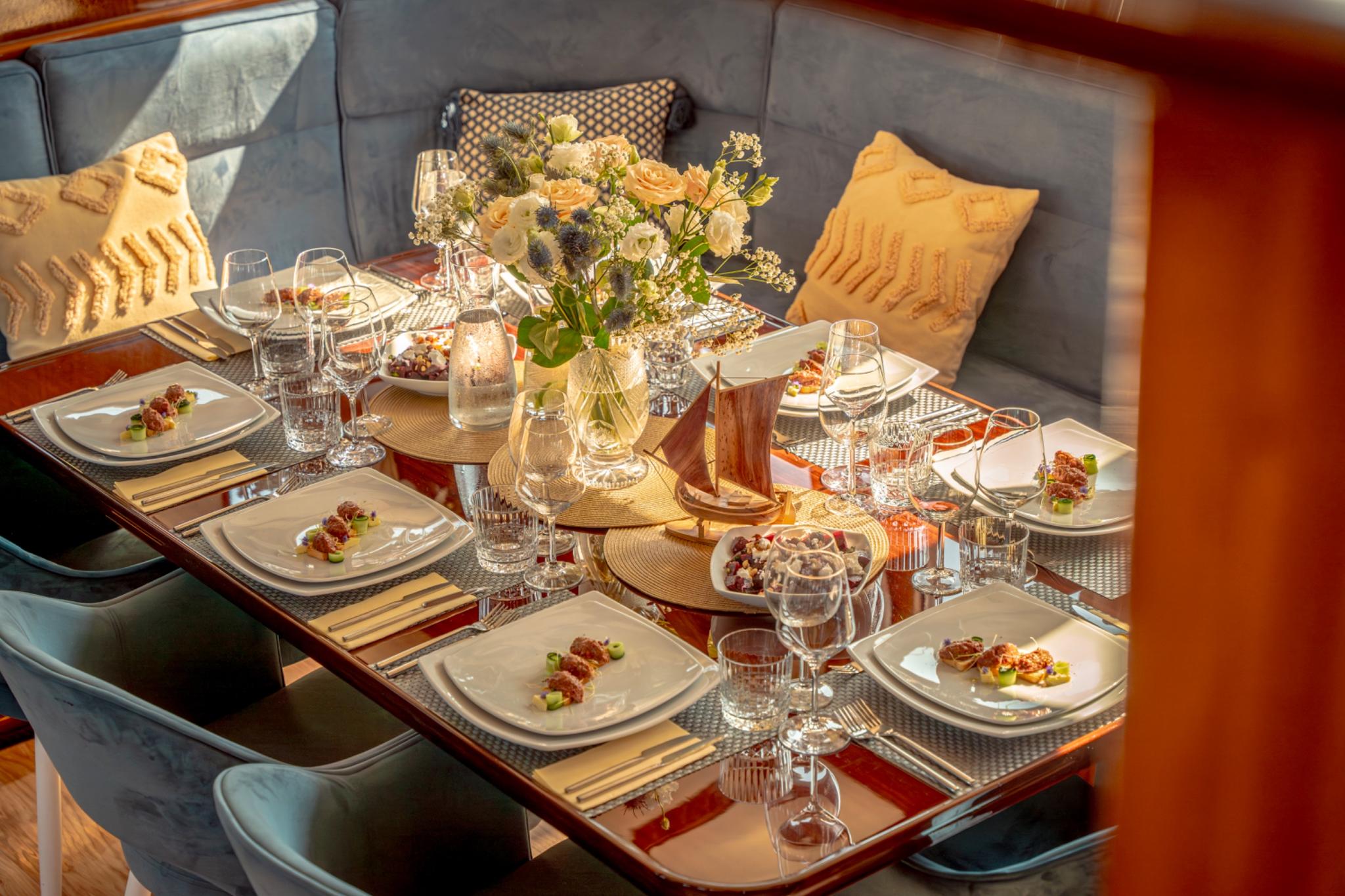 elegant yacht dining table with plated appetizers, wine glasses and fresh flower centerpiece