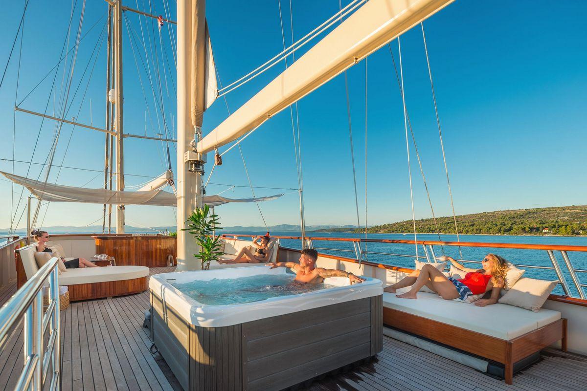 luxury yacht upper deck with hot tub and guests relaxing