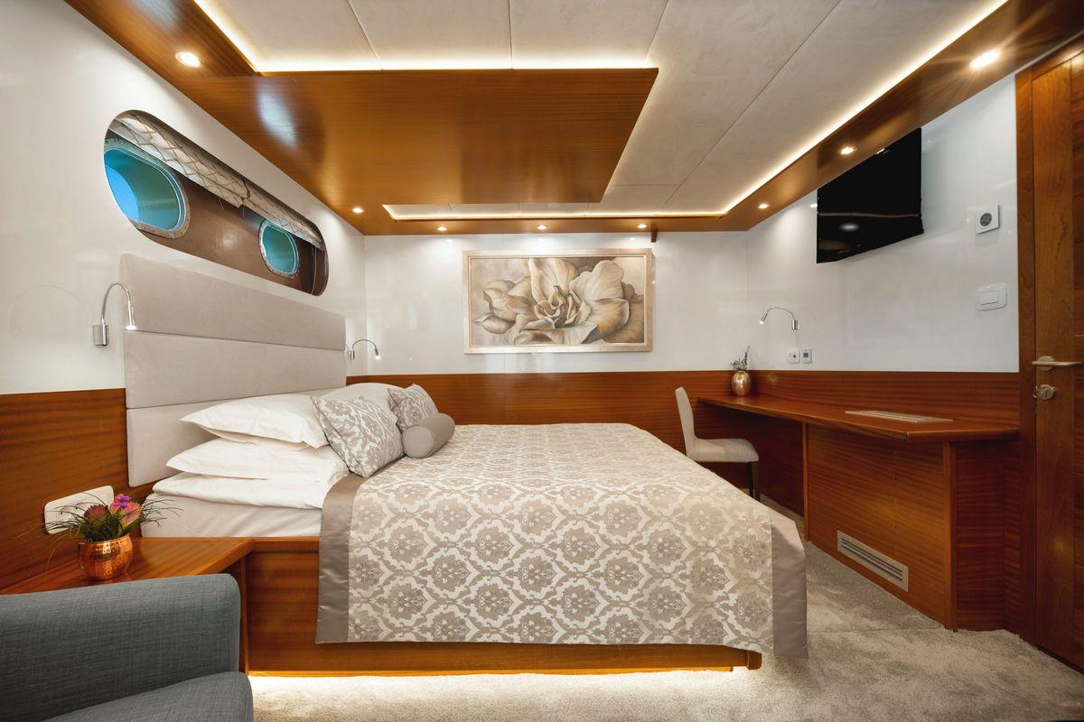 Elegant yacht guest cabin with double bed, teak wood paneling and modern amenities