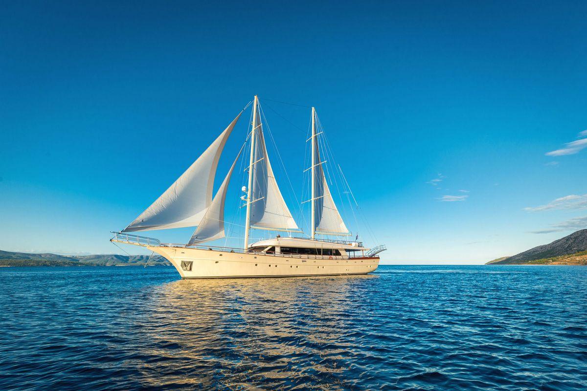 Traditional gulet sailing yacht with white sails anchored in Mediterranean blue waters
