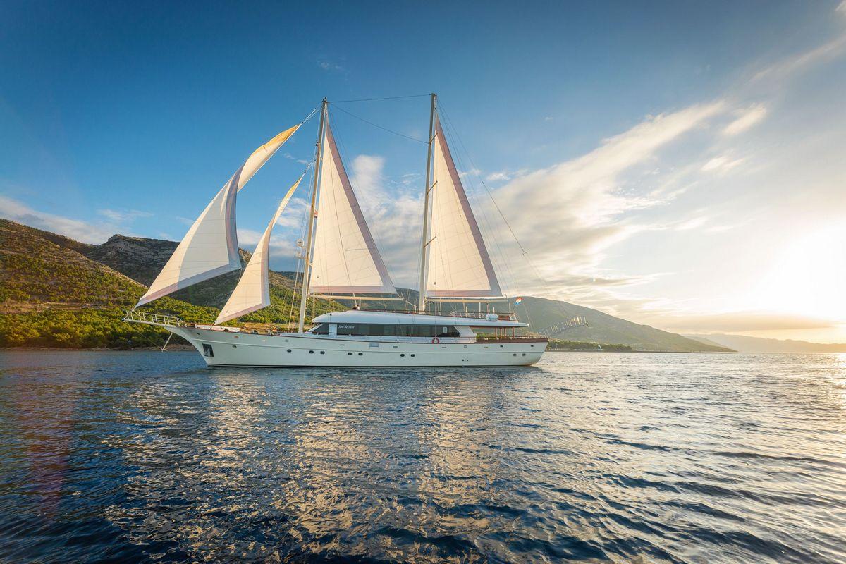 White luxury gulet sailing yacht with raised sails on calm Mediterranean waters