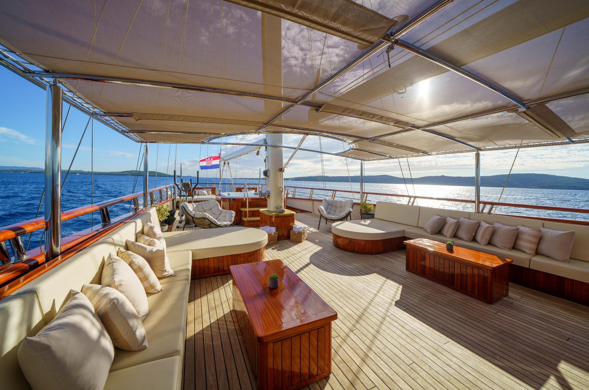 gulet main deck salon with curved seating, coffee tables and canvas awning overhead