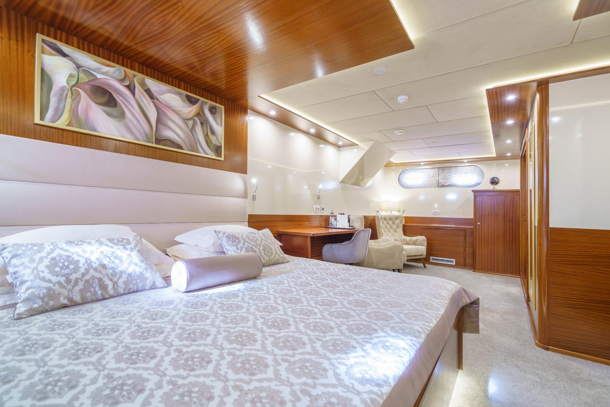 yacht master cabin with king bed white upholstered headboard and teak wood finishes
