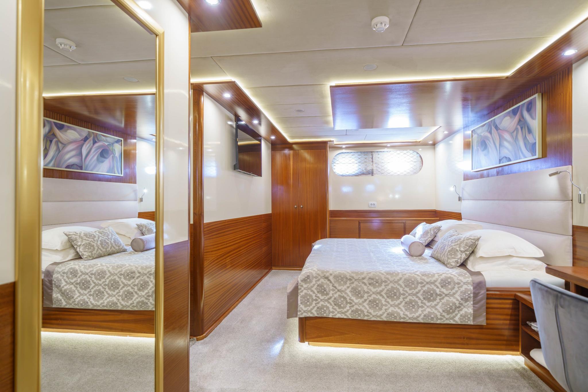 yacht guest cabin featuring twin beds with patterned bedding and full-length mirror