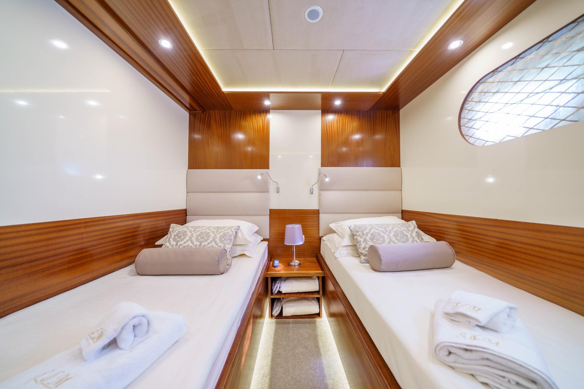 yacht twin cabin featuring two single beds with beige upholstered headboards and wood paneling