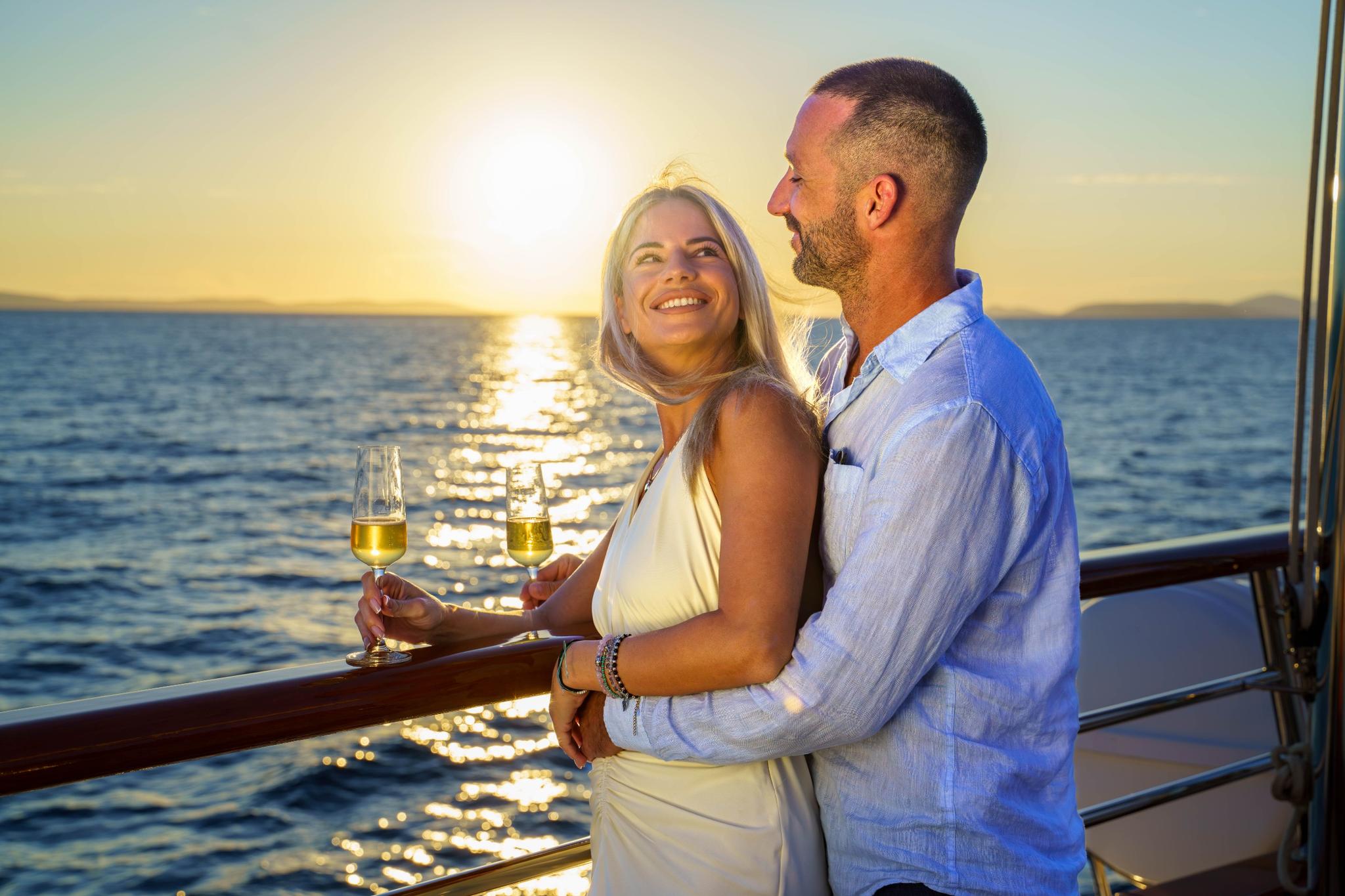 couple celebrating with champagne flutes on yacht deck during golden hour sunset