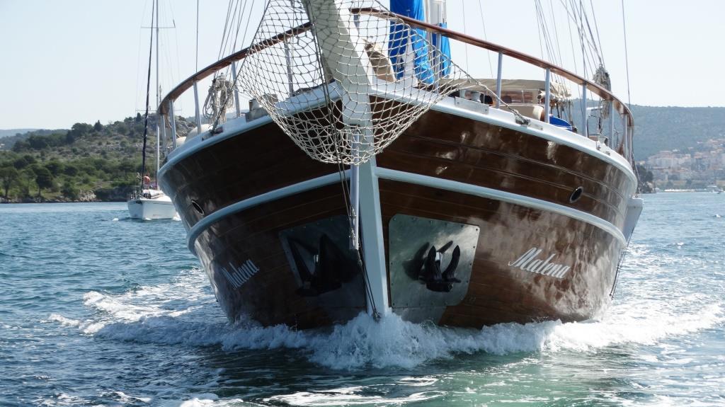 Traditional wooden gulet yacht Matina bow section cutting through blue Mediterranean water