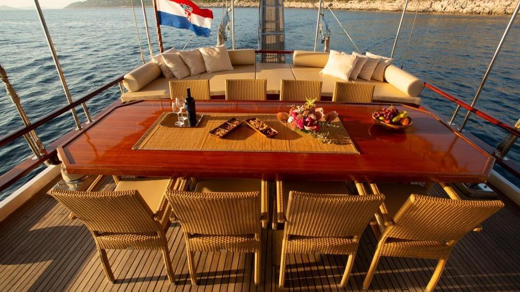 luxury yacht aft deck dining area with mahogany table and wicker chairs
