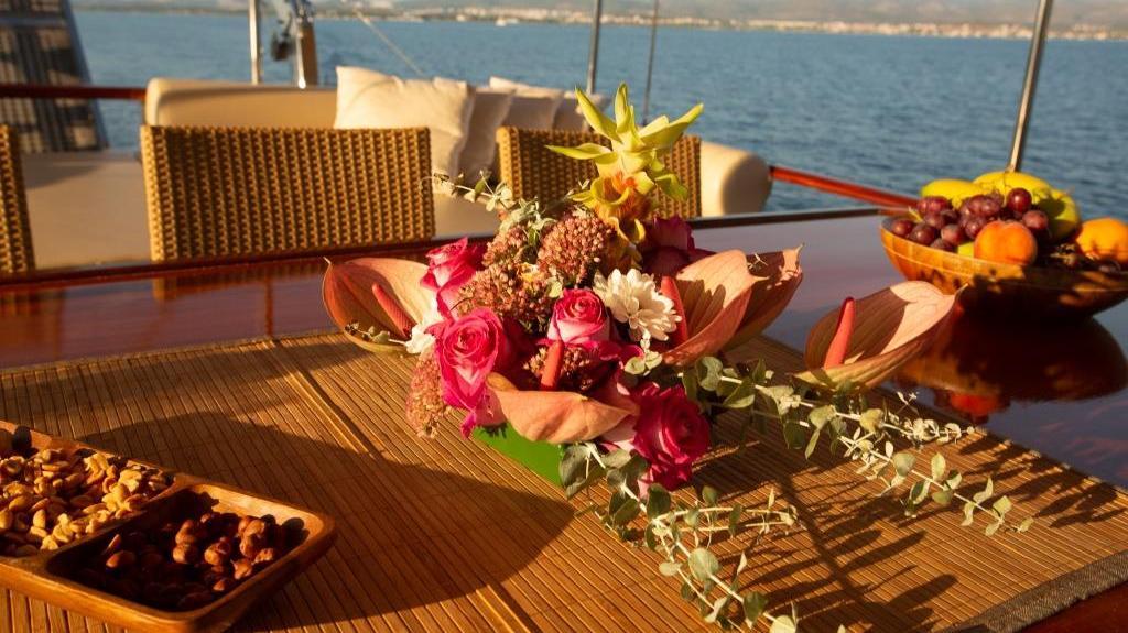 Elegant yacht dining setup with flowers and fruit during golden hour