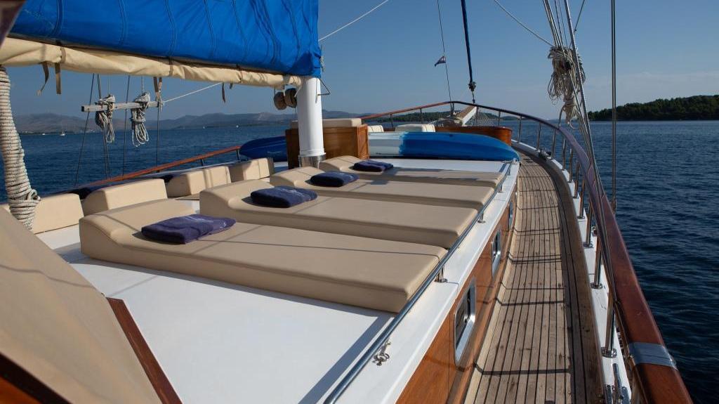 yacht forward deck sunbathing area with cream mattresses and blue cushions