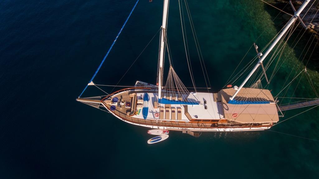 Aerial view of wooden gulet yacht with two masts anchored in turquoise Mediterranean waters