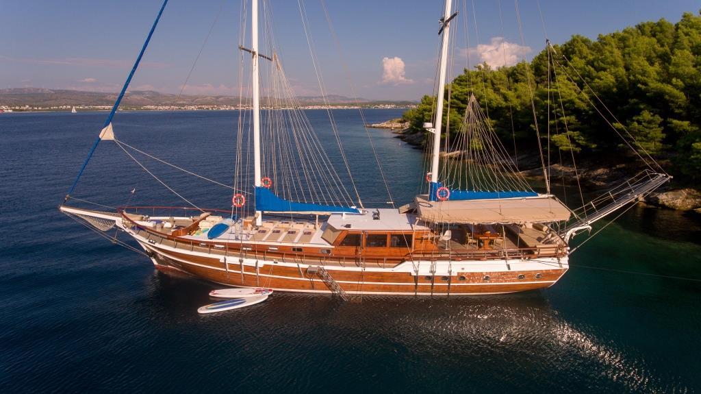Traditional wooden gulet yacht anchored in crystal clear turquoise Mediterranean bay
