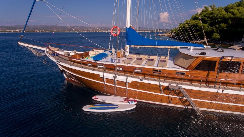 Classic wooden gulet yacht with white striped hull anchored in Mediterranean waters