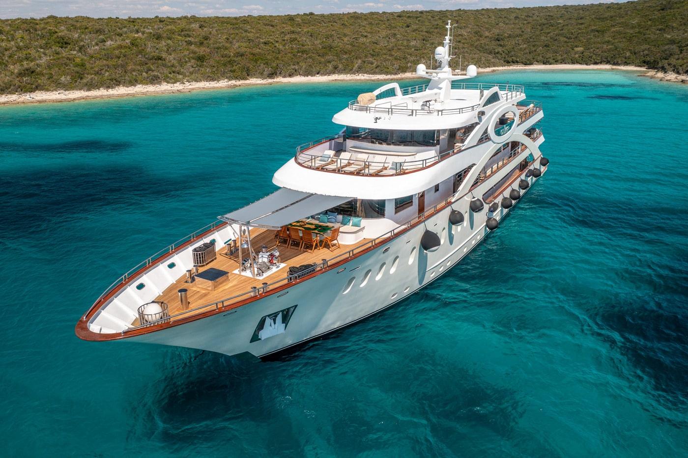 White luxury motor yacht with multiple decks anchored in crystal clear turquoise waters