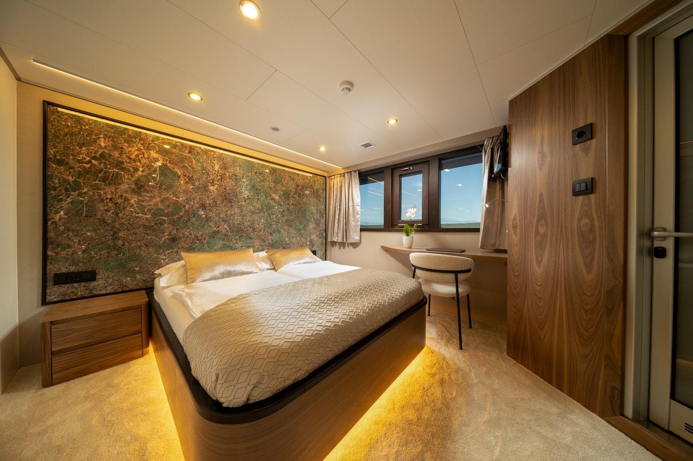 luxury yacht master cabin featuring illuminated bed and marble headboard wall