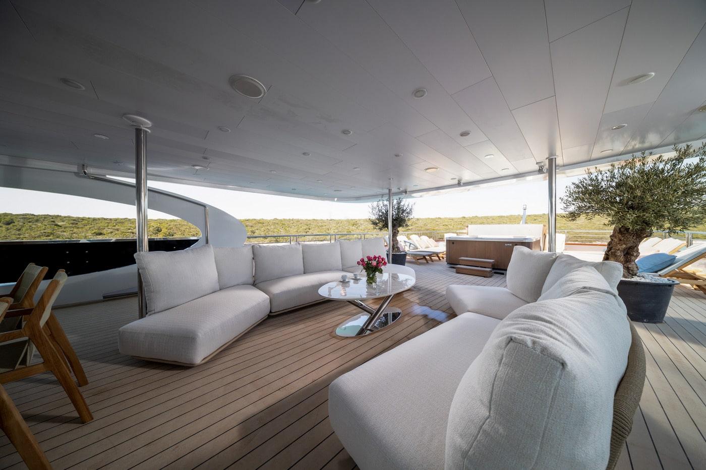 luxury yacht covered aft deck lounge area with gray furniture and teak decking