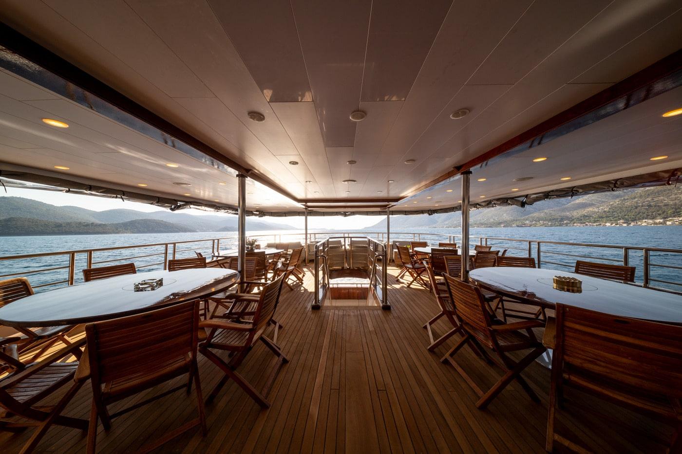luxury yacht aft deck dining area with white tables teak chairs